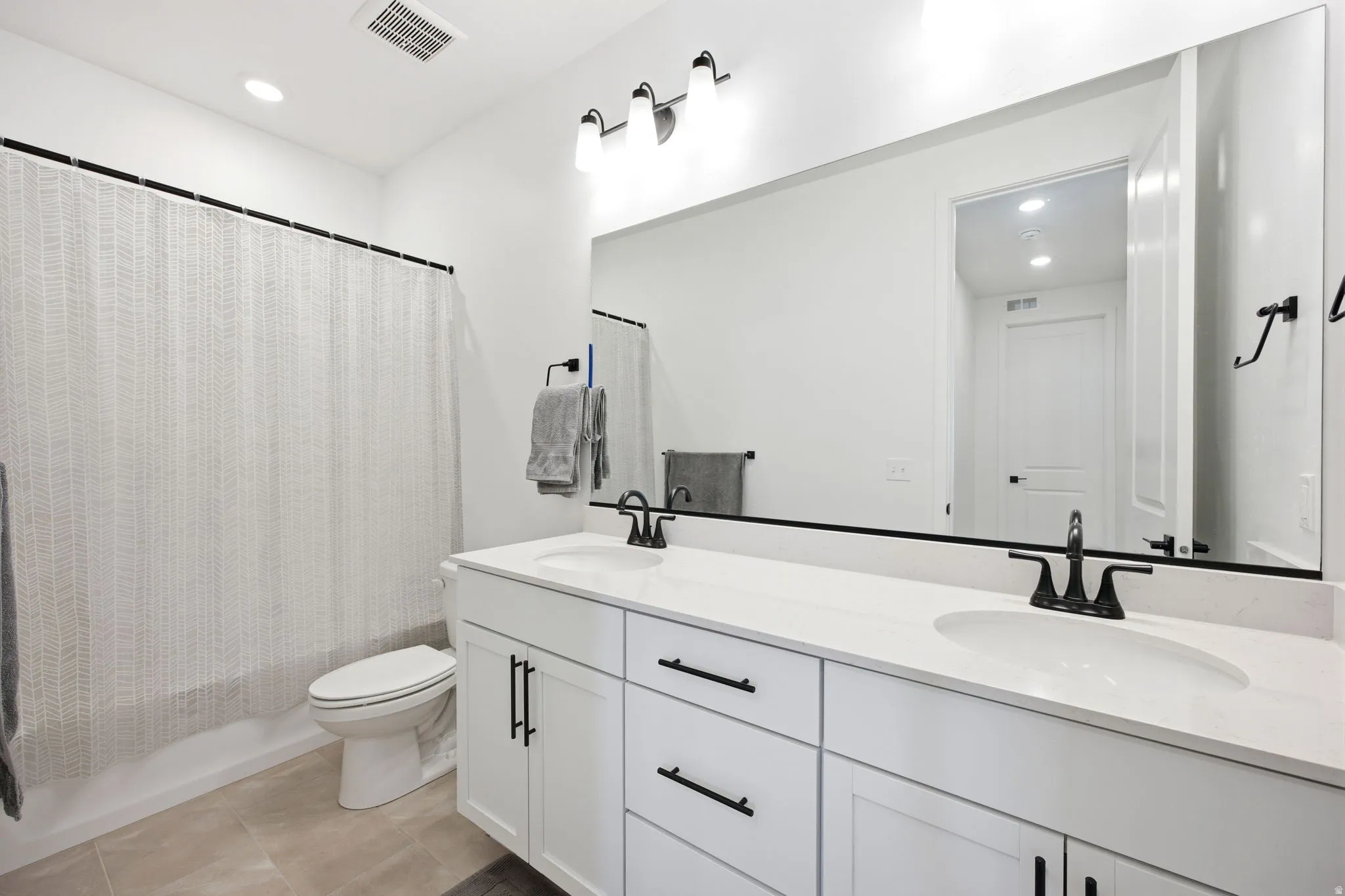 White double vanity with integrated sinks, quartz countertop, and matte black hardware