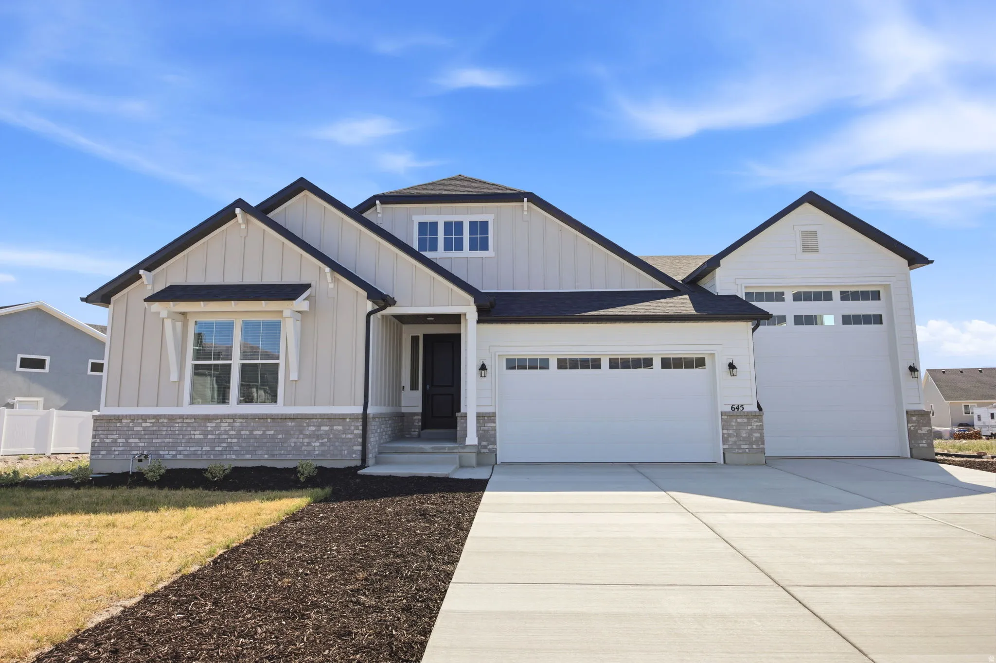 Modern farmhouse-style exterior featuring light-toned vertical siding and dark trim