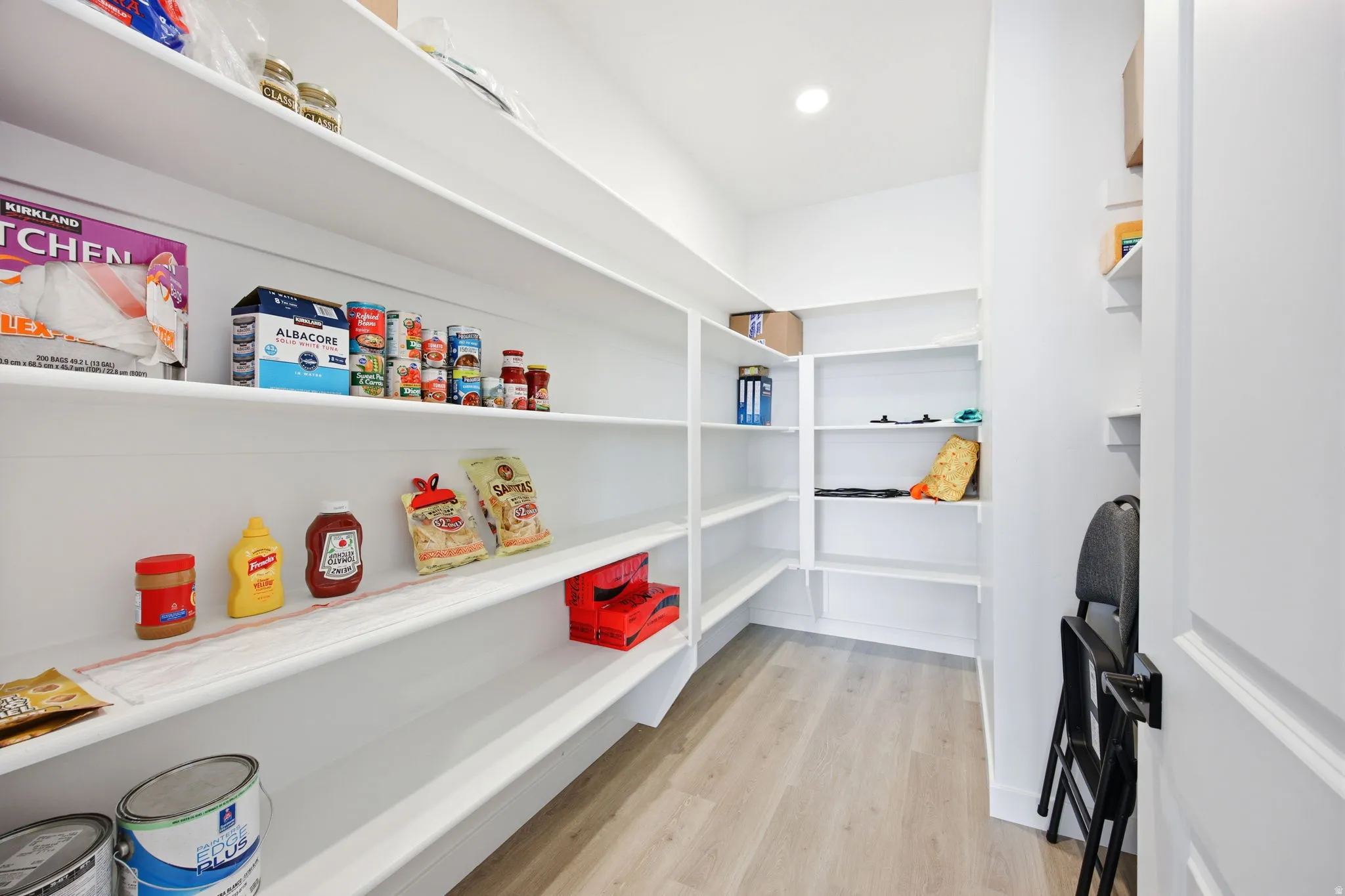 Walk-in pantry featuring extensive built-in shelving, recessed lighting, and wood-finish flooring
