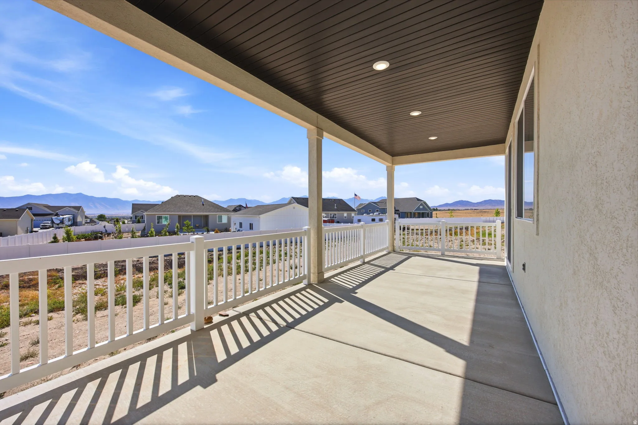 Expansive covered patio with a concrete surface and white railing