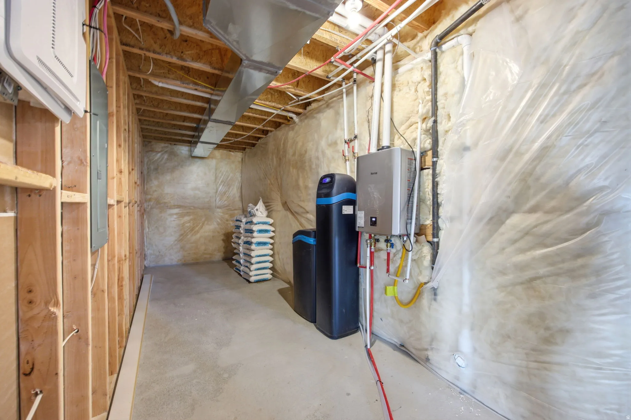 Unfinished basement featuring a water heater, water softener, exposed framing, and ductwork