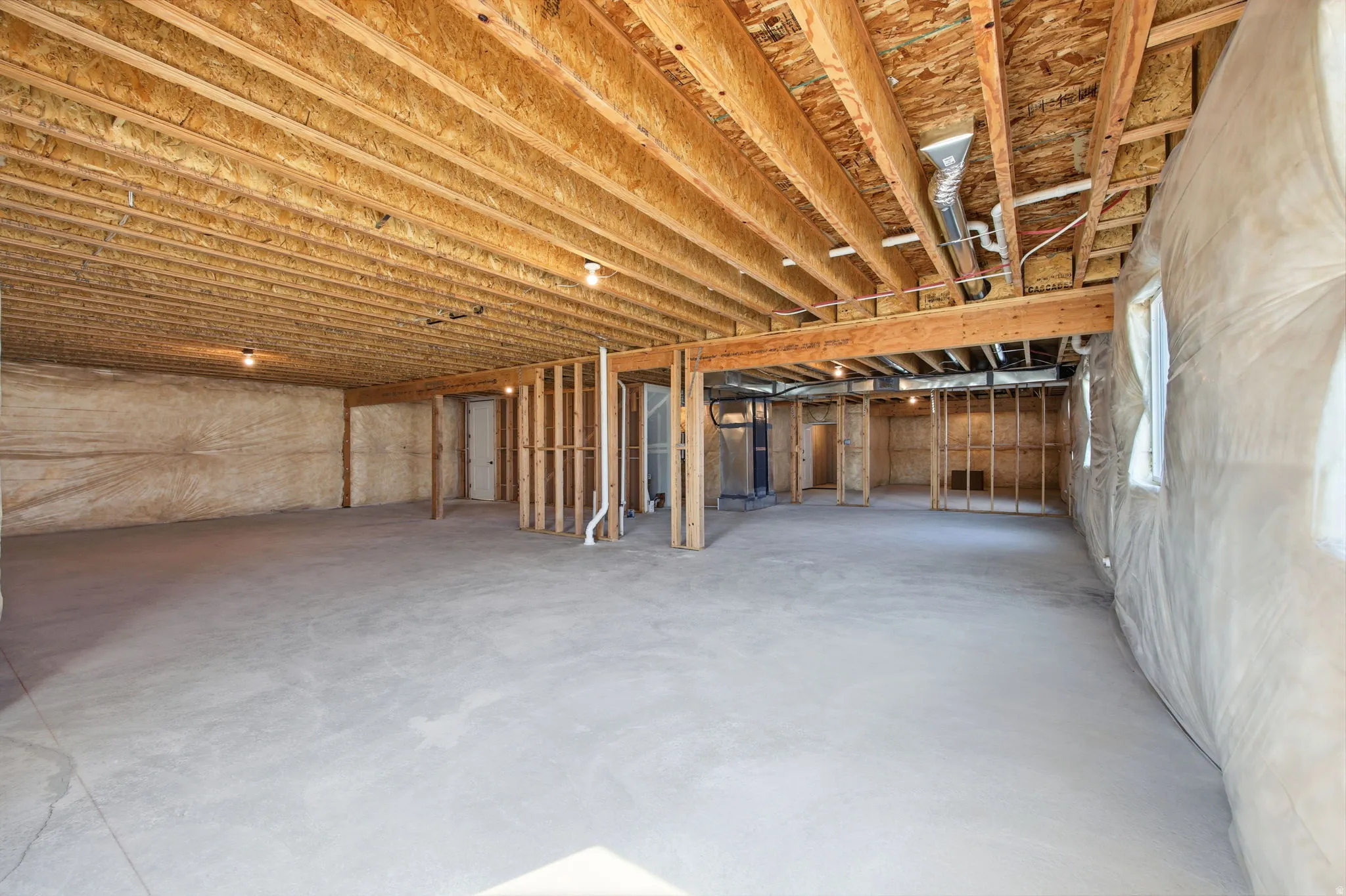 Unfinished basement featuring a concrete floor and exposed wood joists