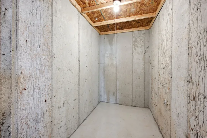 Unfinished room featuring concrete walls, concrete flooring, and an exposed plywood ceiling
