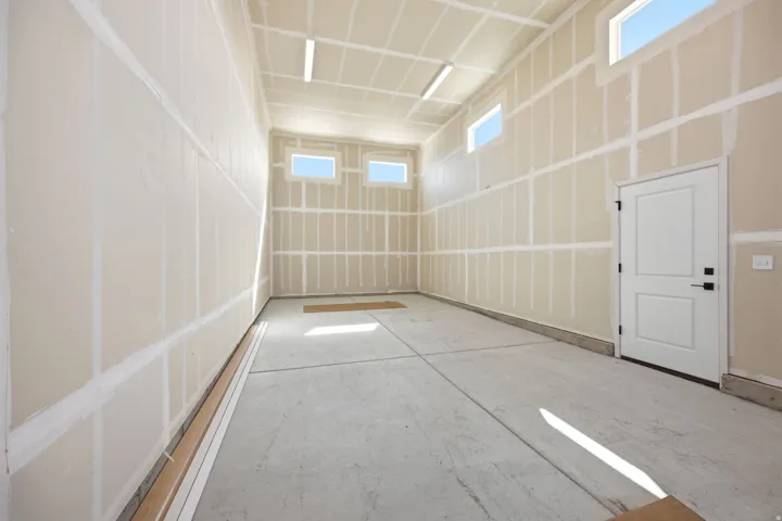 RV garage featuring a concrete floor, unpainted drywall, high ceilings, multiple upper transom windows, and a white interior door with black hardware