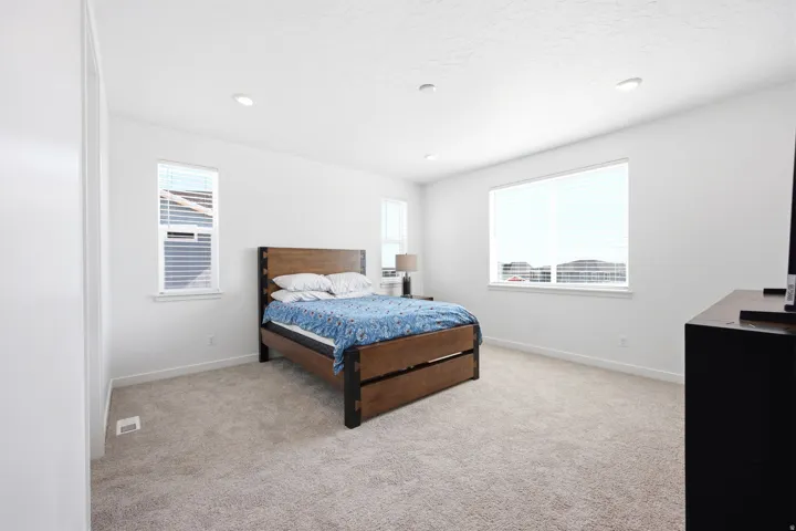Spacious room featuring neutral carpeting, recessed lighting, white walls, and multiple windows with blinds