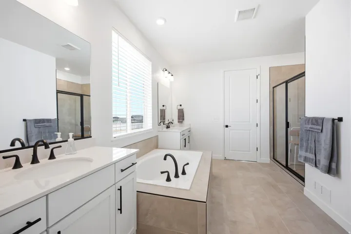 Contemporary bathroom featuring a built-in soaking tub, a separate glass-enclosed shower, and dual vanities with integrated sinks