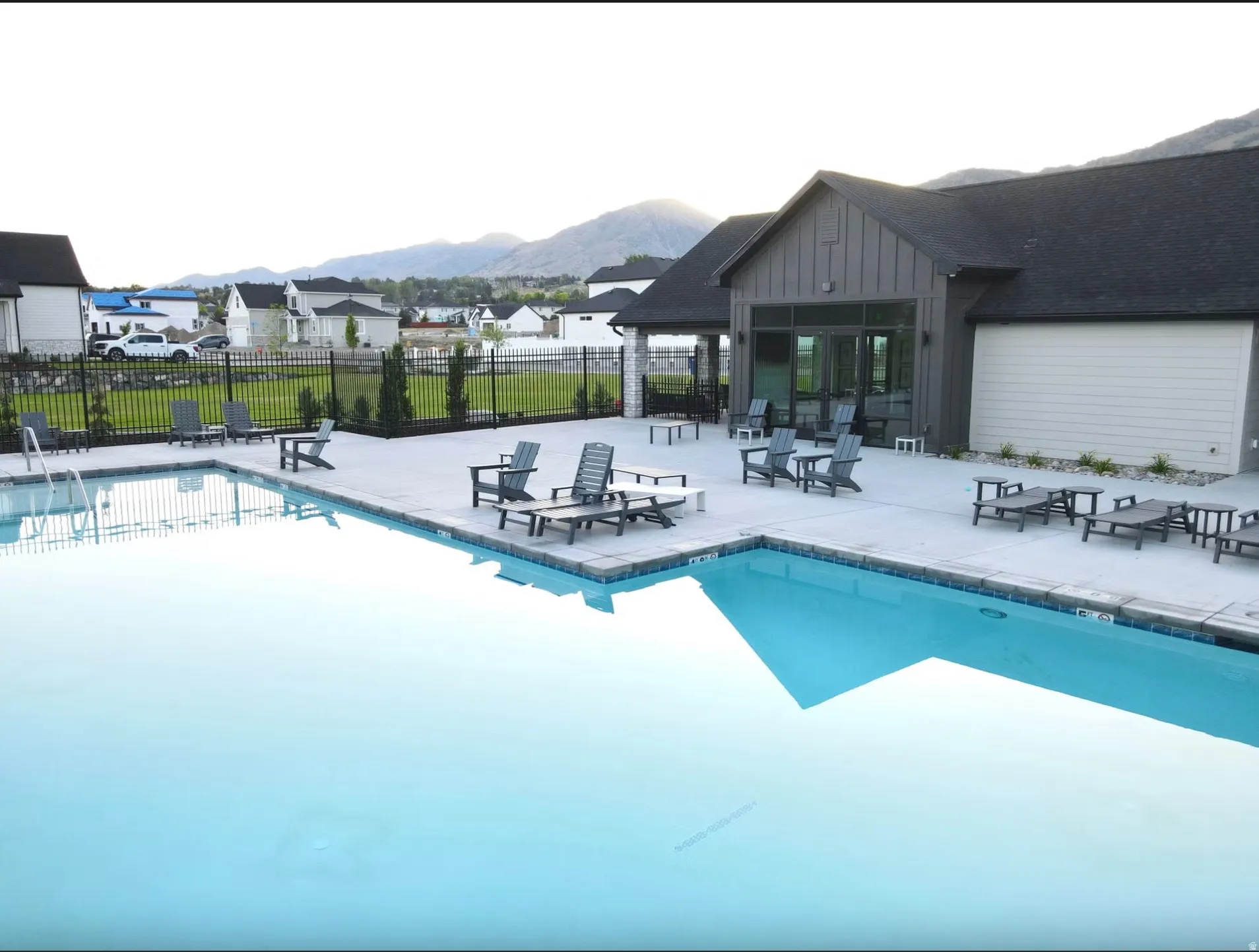 Outdoor swimming pool with integrated steps, surrounded by a concrete deck with lounge seating