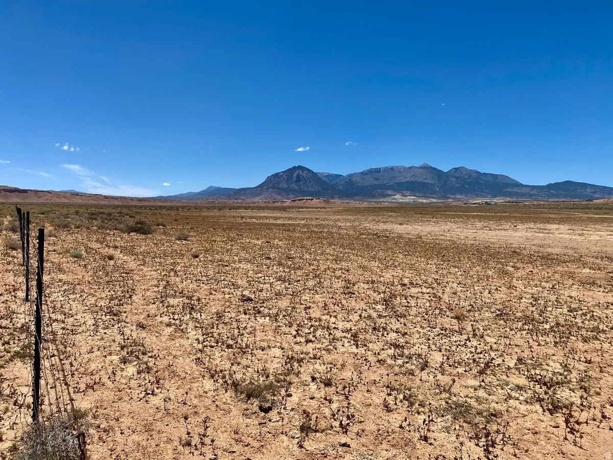 Expansive open land with distant mountain ranges and a clear blue sky