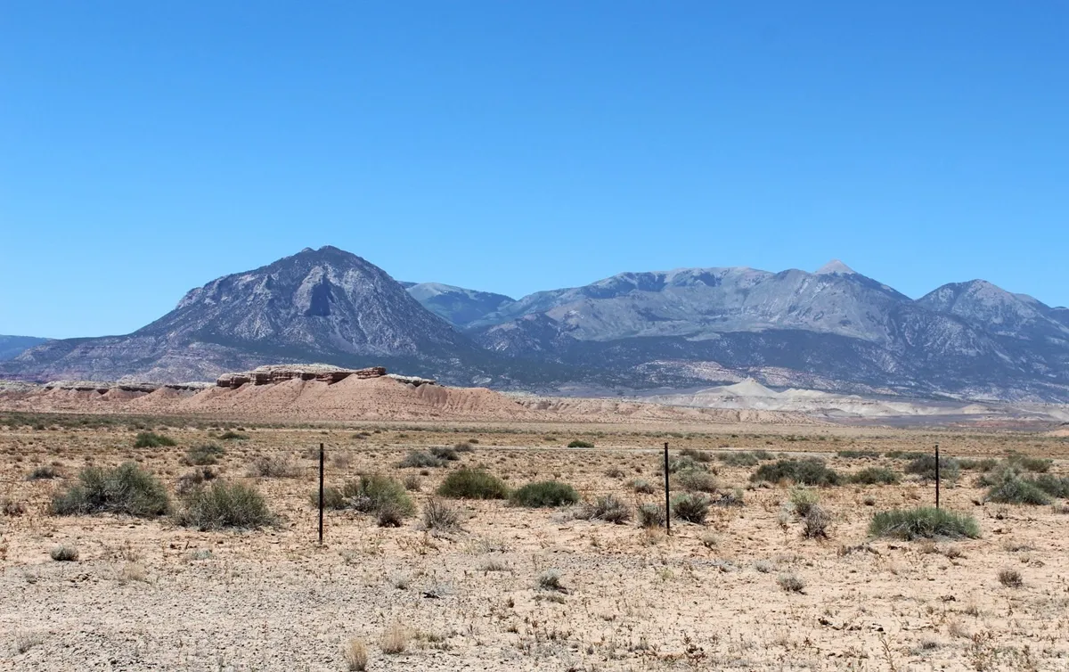 Expansive desert landscape featuring natural rock formations and distant mountains under a clear sky