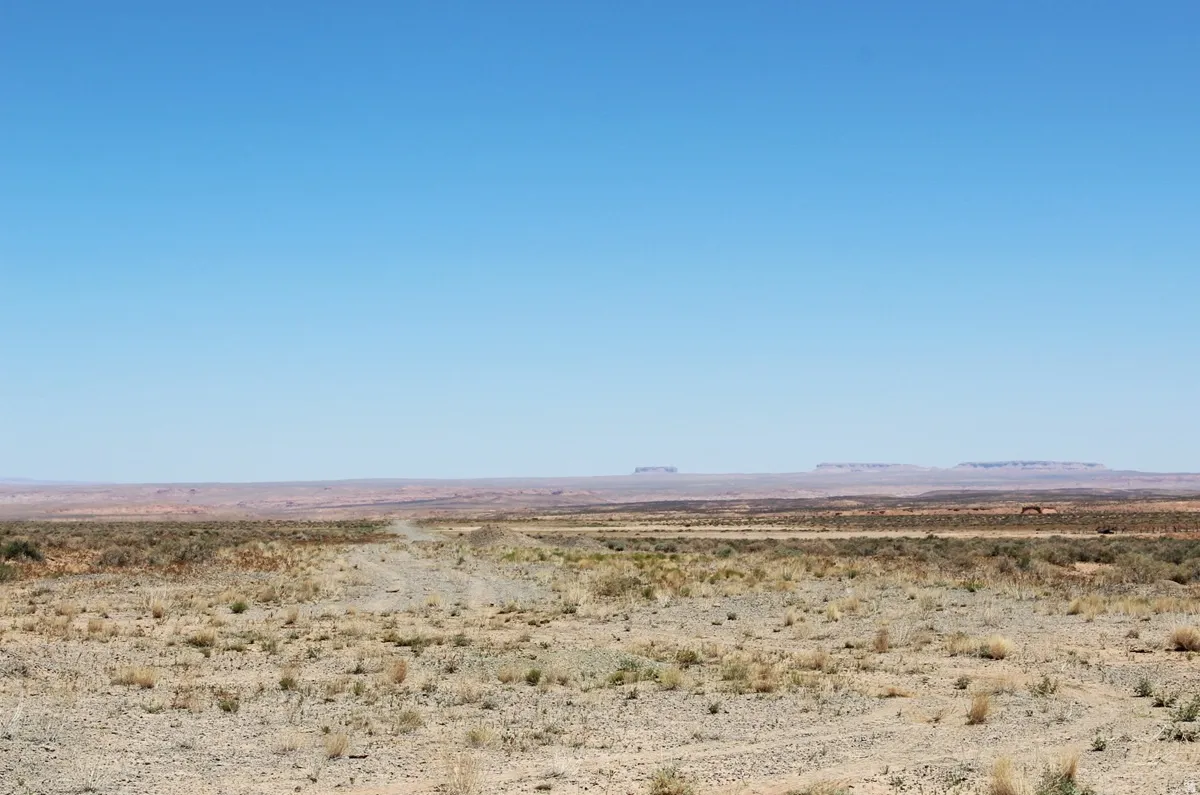 Unobstructed desert landscape with a dirt road extending into the distance