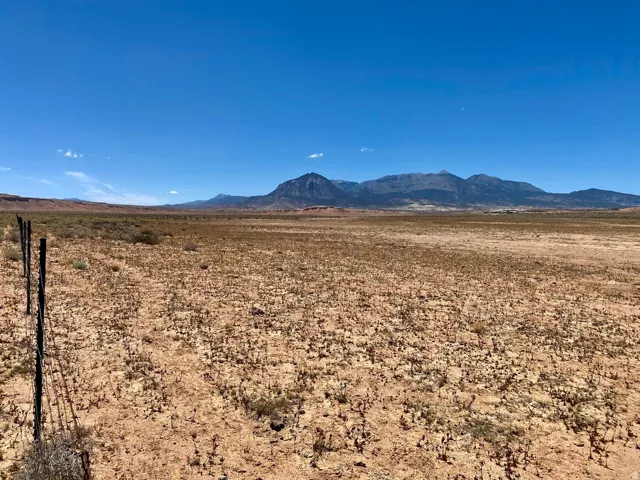 Expansive open land with distant mountain ranges and a clear blue sky