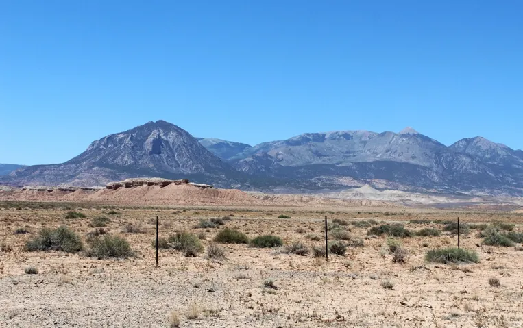 Expansive desert landscape featuring natural rock formations and distant mountains under a clear sky
