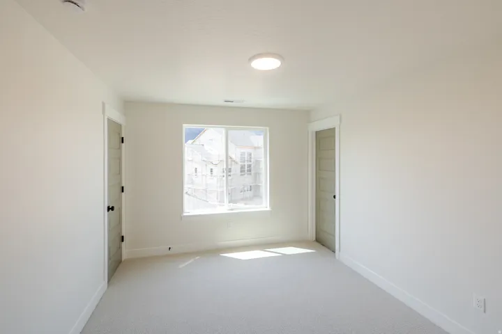 Spacious room featuring neutral carpeting, a large window, and recessed lighting