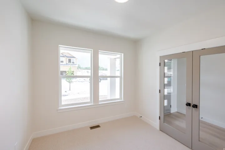 Neutral wall finishes and light-colored carpeting complement the natural light from dual windows