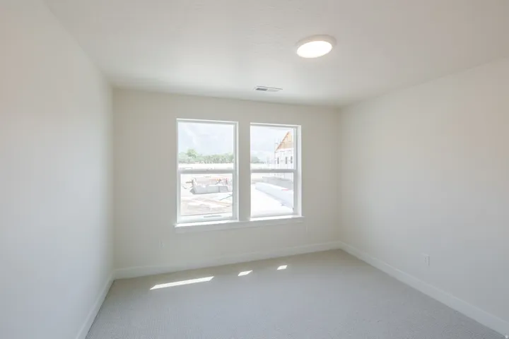 Light-filled room featuring neutral wall tones and a soft grey carpet