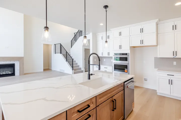 Kitchen island featuring a white countertop with prominent veining, an undermount sink with a black coiled faucet, and wood-finish cabinetry