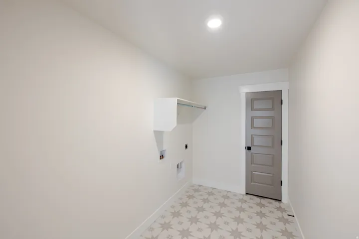 Laundry area featuring a gray panel door, recessed lighting, and patterned floor tile