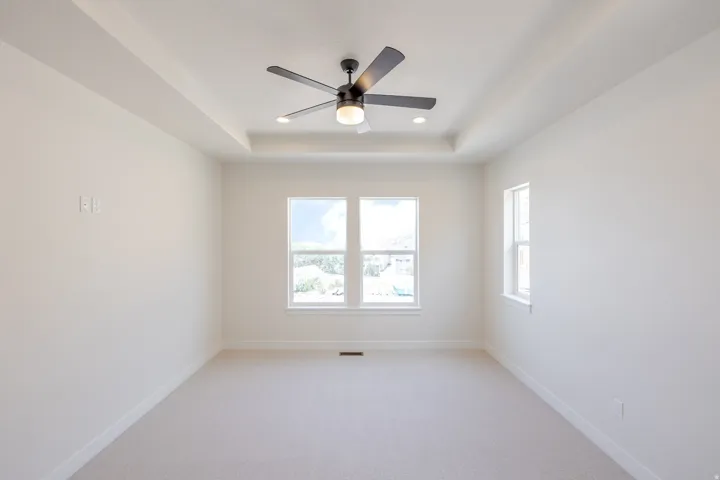 Spacious room featuring a tray ceiling with recessed lighting and a ceiling fan