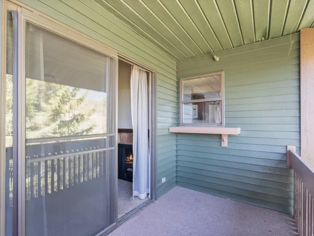 Outdoor balcony featuring light green siding, a sliding glass door, and a built-in window shelf