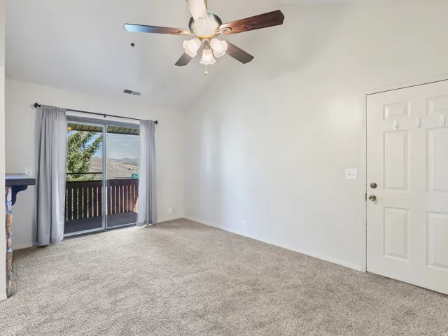 Spacious room featuring vaulted ceilings, light neutral wall paint, and plush carpeting
