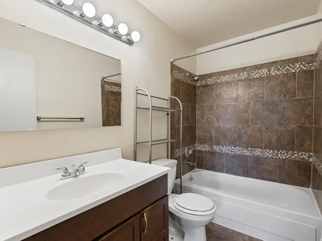Full bathroom featuring a vanity with a white countertop, chrome faucet, and a large wall-mounted mirror