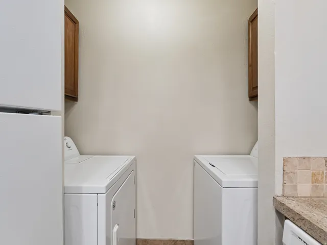 Dedicated laundry area featuring a washer and dryer, upper cabinetry, and tile flooring