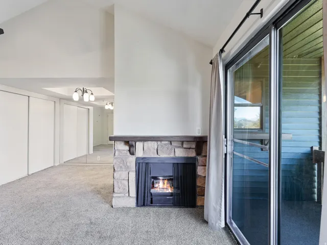 Vaulted ceilings complement a stone-clad fireplace with a wood mantel