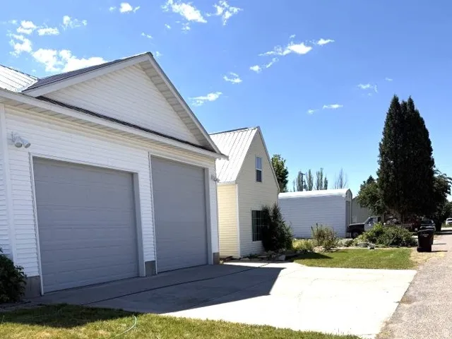 Two-car garage with light gray doors and white vinyl siding