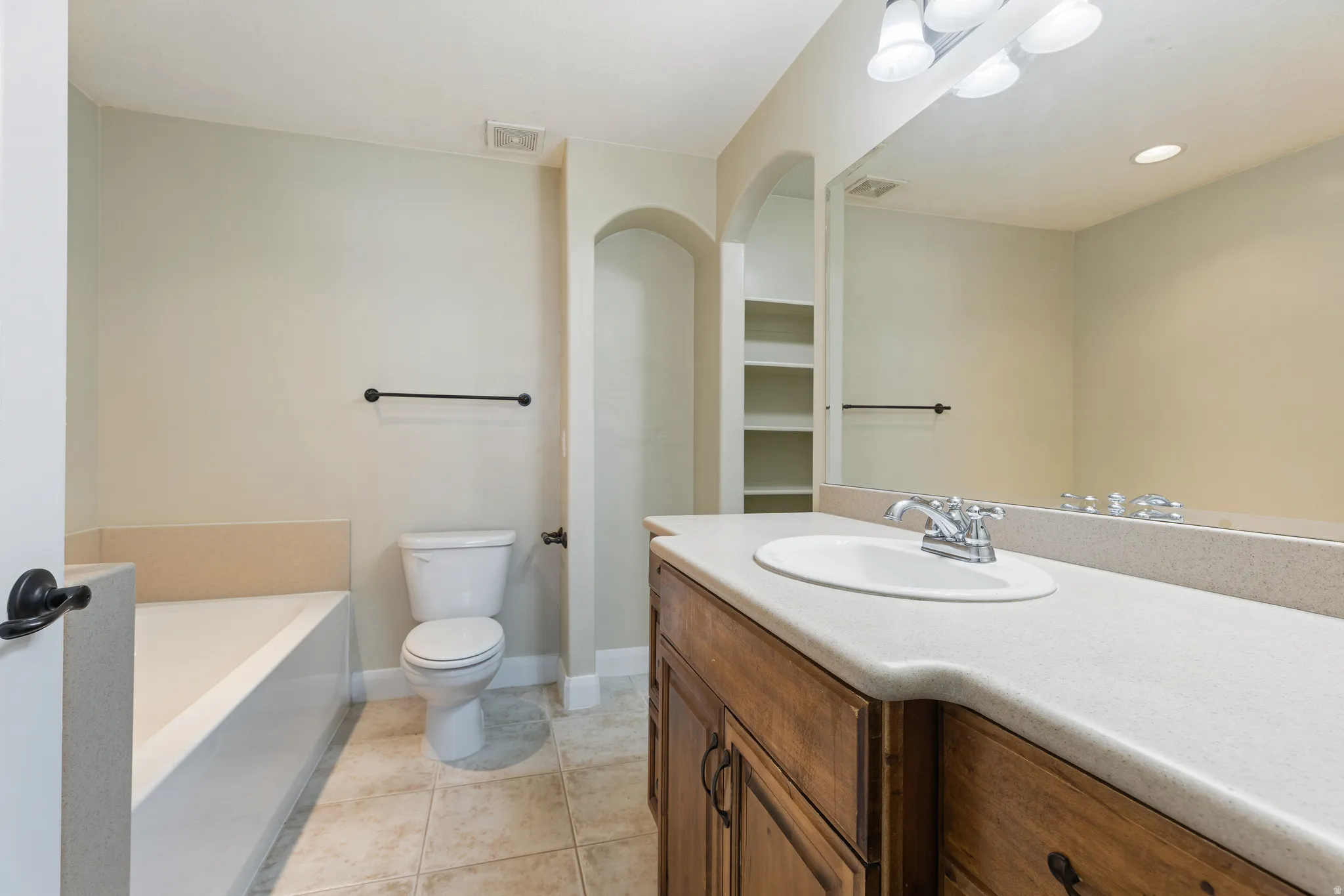 Bathroom featuring a wood-finish vanity with a light countertop and an integrated sink