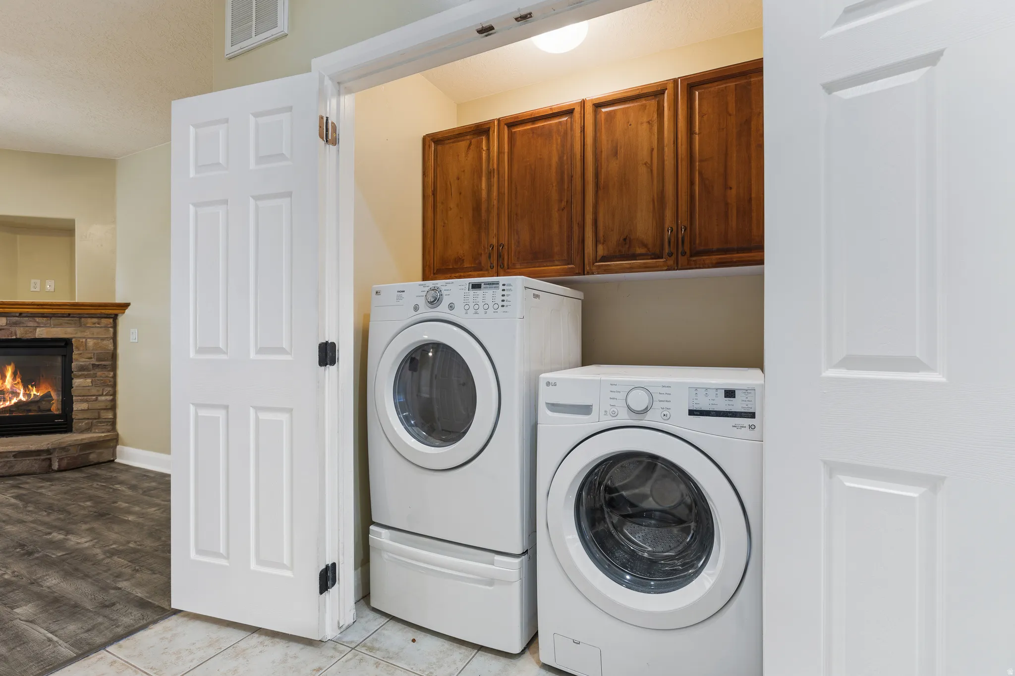 Dedicated laundry area featuring tile flooring, wood-finish cabinetry, and overhead lighting