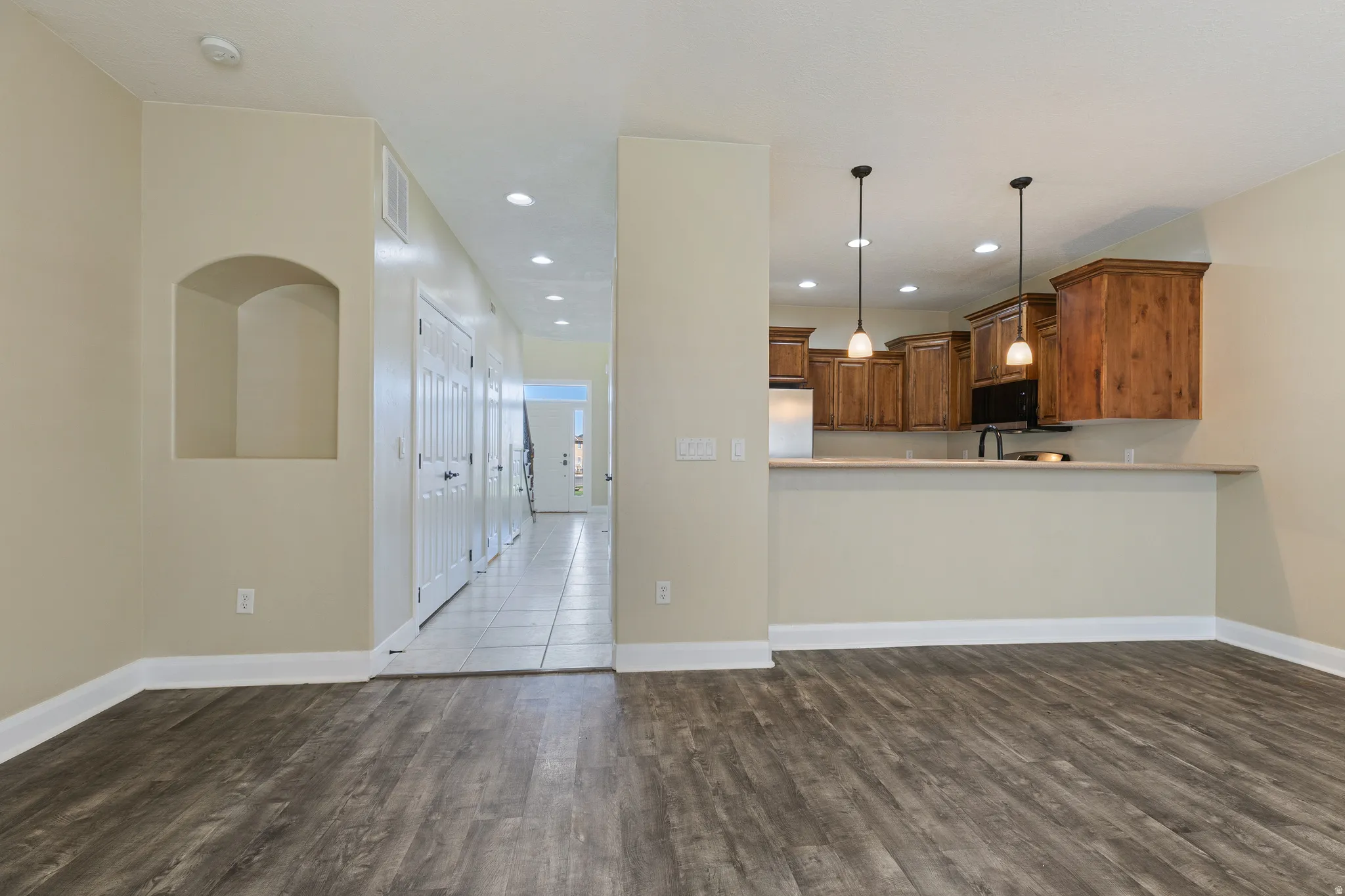 Open-concept living space with wood-finish flooring extending into the kitchen area
