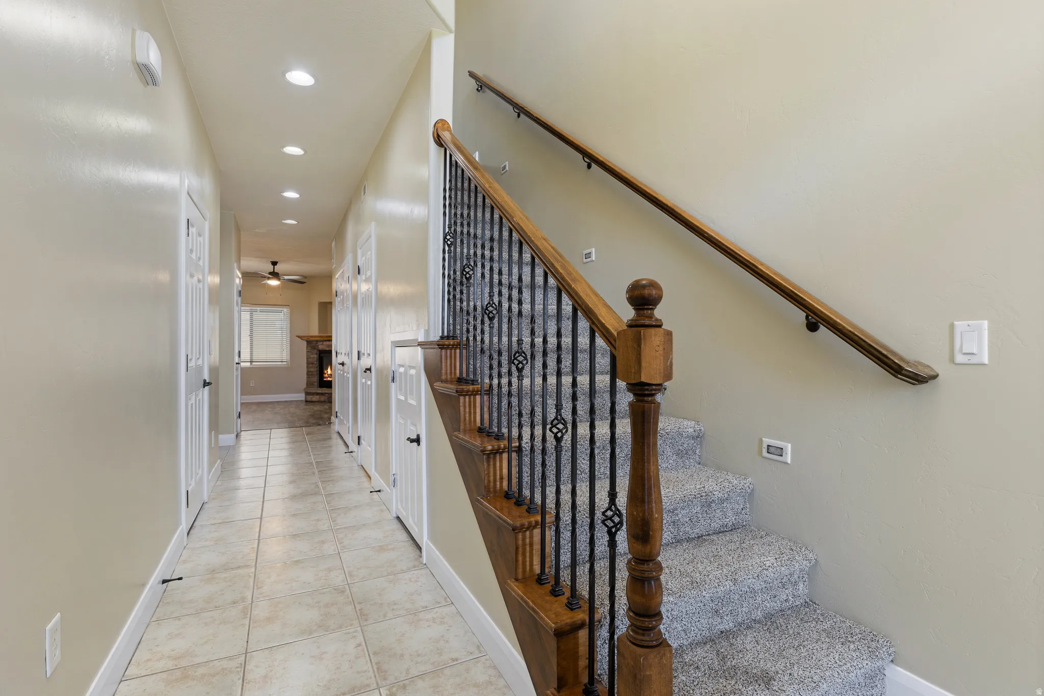 Staircase featuring wood newel posts, wrought iron balusters, and carpeted treads