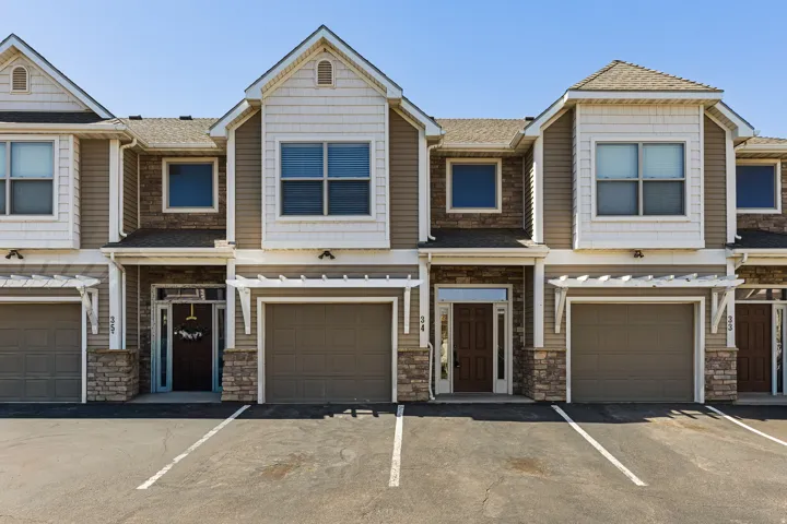 Townhome exterior featuring tan siding, stone accents, and pitched roofs