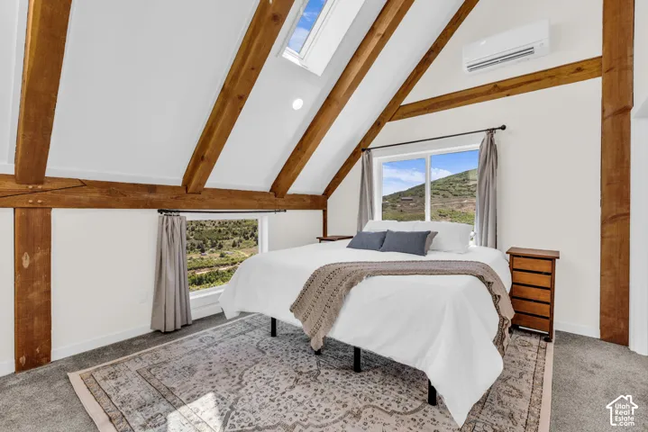 Vaulted ceilings with exposed wood beams, skylight, and large window framing a mountain backdrop