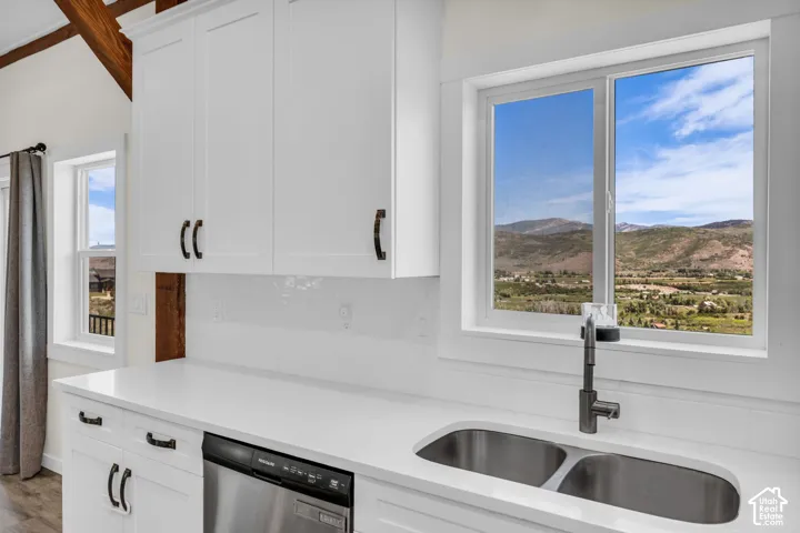 Kitchen featuring white shaker cabinetry, stainless steel double basin sink, and a modern gooseneck faucet