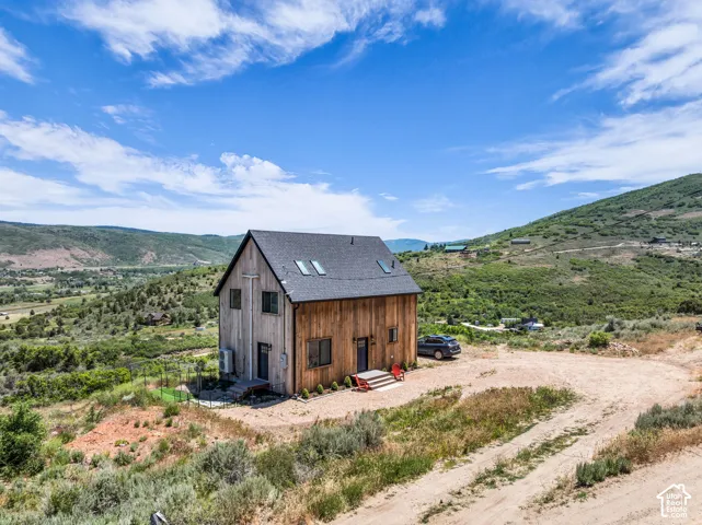 Modern rustic home featuring natural wood siding, a dark pitched roof, and multiple skylights