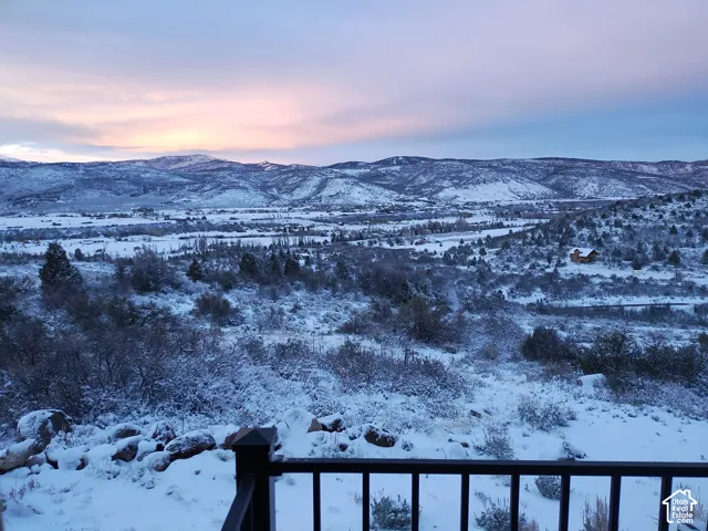 Expansive mountain scenery featuring snow-covered peaks, a valley, and scattered evergreen trees