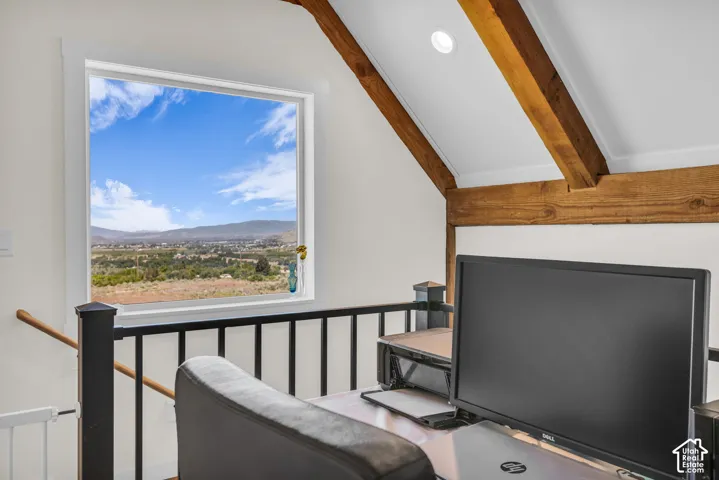 Open loft space featuring exposed wood beams, recessed lighting, and a prominent window
