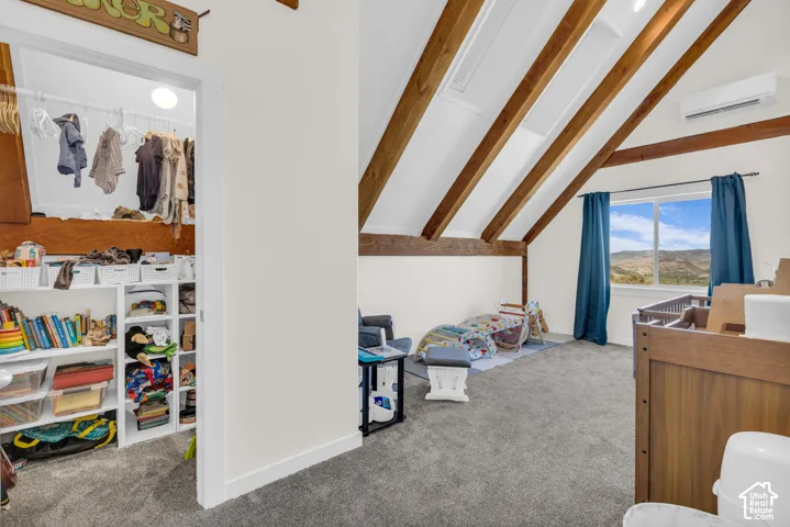 Room featuring exposed wood beams, a window with a distant landscape, carpeting, a ceiling-mounted mini-split unit, and a walk-in closet with built-in shelving