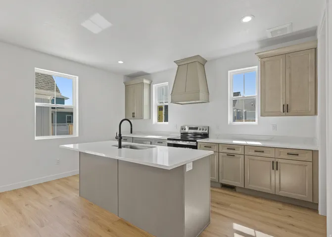 Contemporary kitchen featuring a center island with sink, white countertops, coordinating cabinetry, a range with hood, and wood-finish flooring