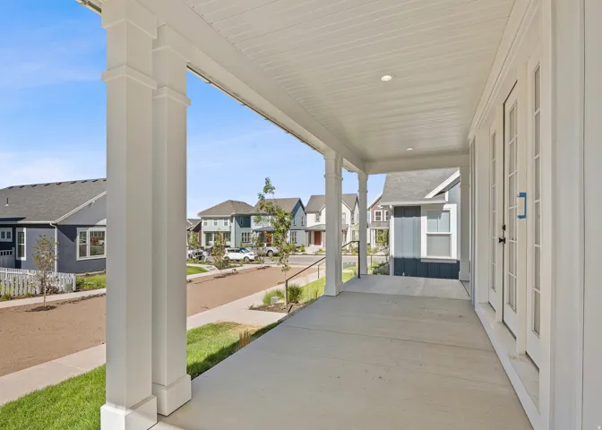 Inviting covered front porch with substantial white architectural columns, recessed lighting, and a concrete surface