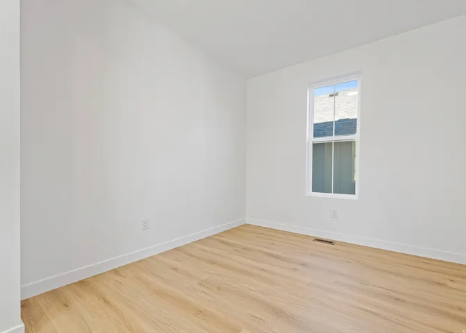 Bright room featuring light wood-finish flooring and crisp white walls