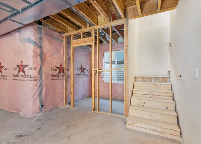 Unfinished basement featuring exposed wood framing, concrete flooring, and partial insulation