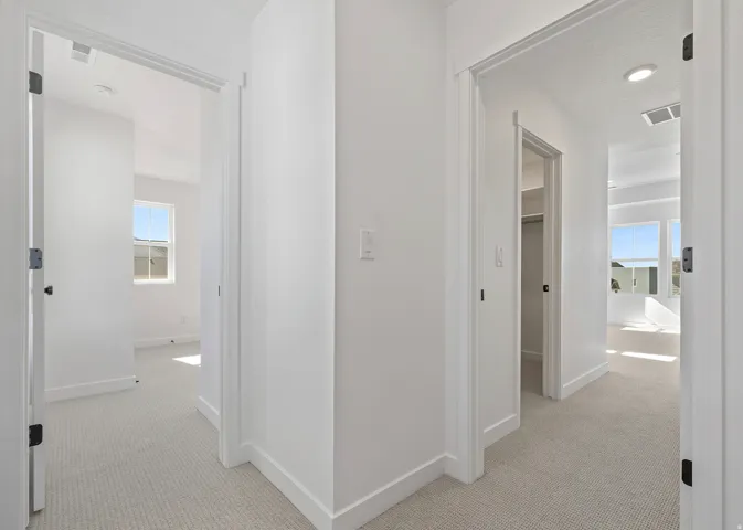 Hallway featuring light-colored carpet flooring, white walls, and white trim