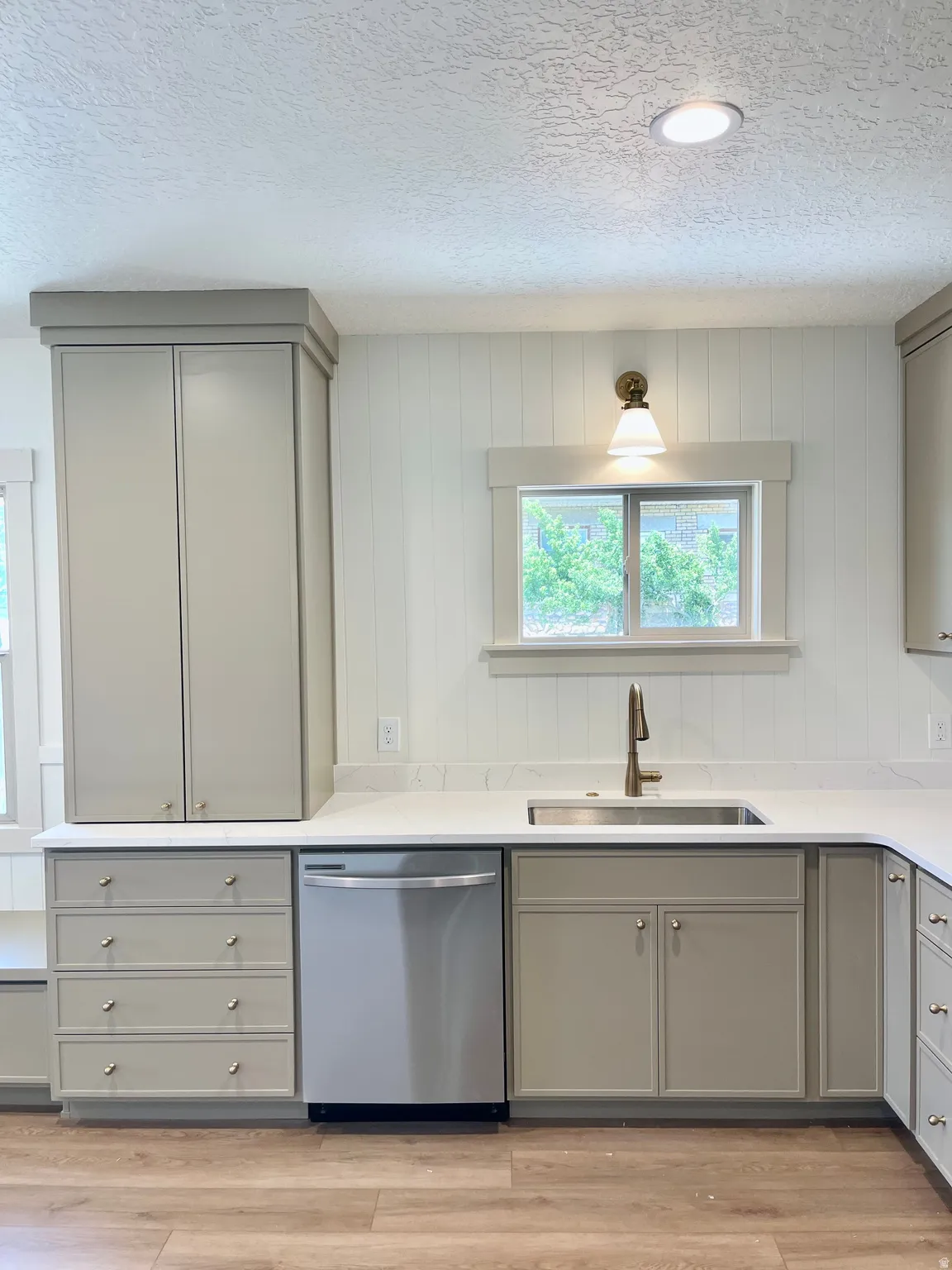 Kitchen featuring light-toned cabinetry with crown molding, stainless steel sink, and a modern faucet