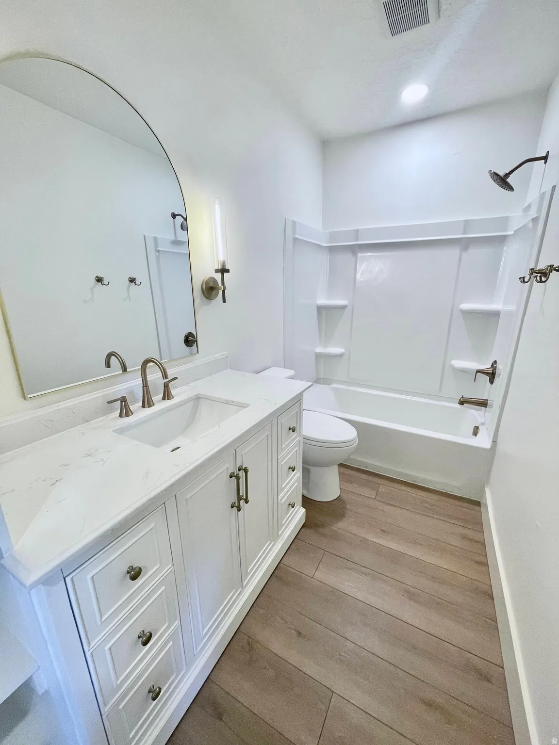 White vanity with an integrated sink, brushed nickel faucet, and a light-toned wood-finish floor