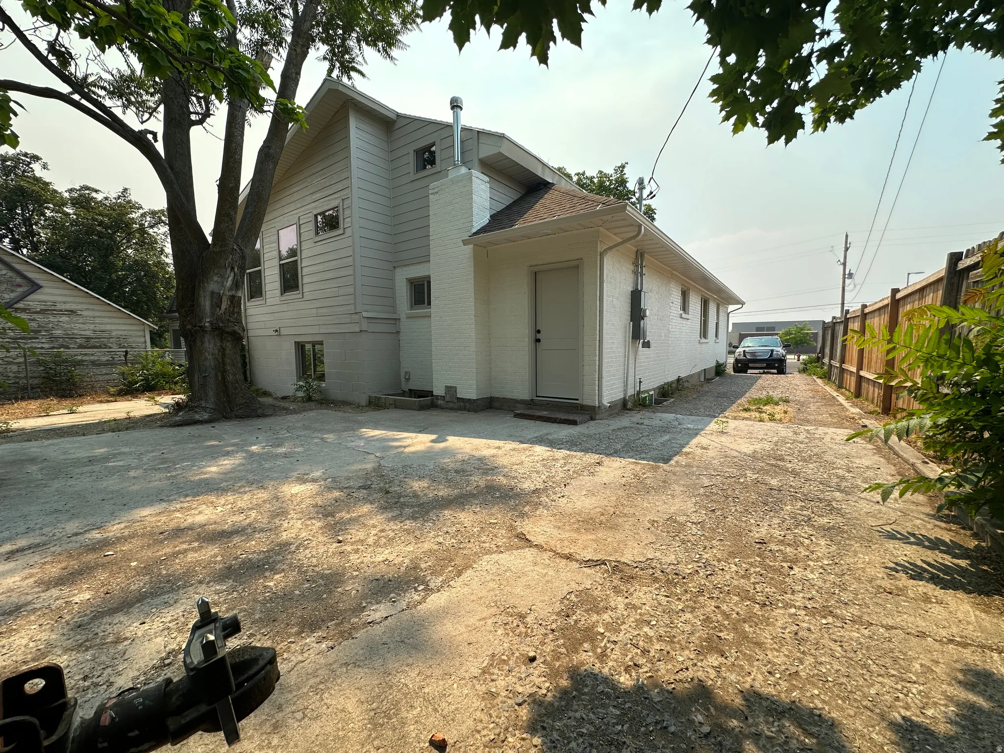 White painted brick and siding exterior with a large mature tree