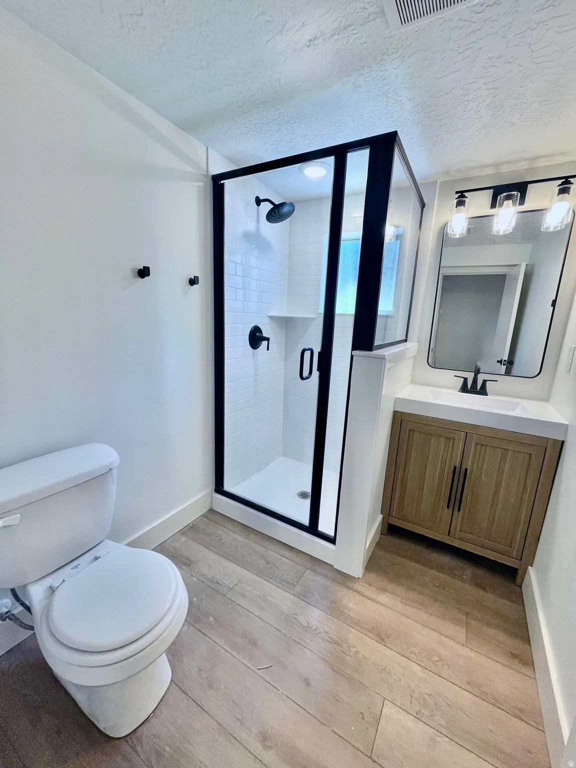 Bathroom featuring a glass-enclosed shower with black framing, white subway tile surround, and black fixtures