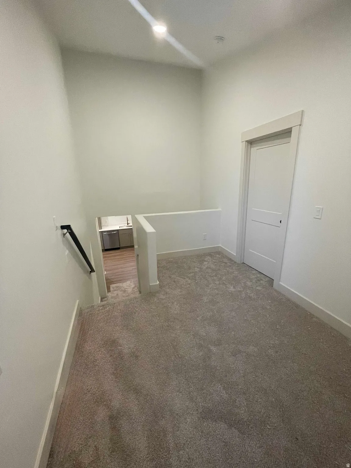Carpeted landing with white walls and trim, featuring a contemporary white door with simple paneling