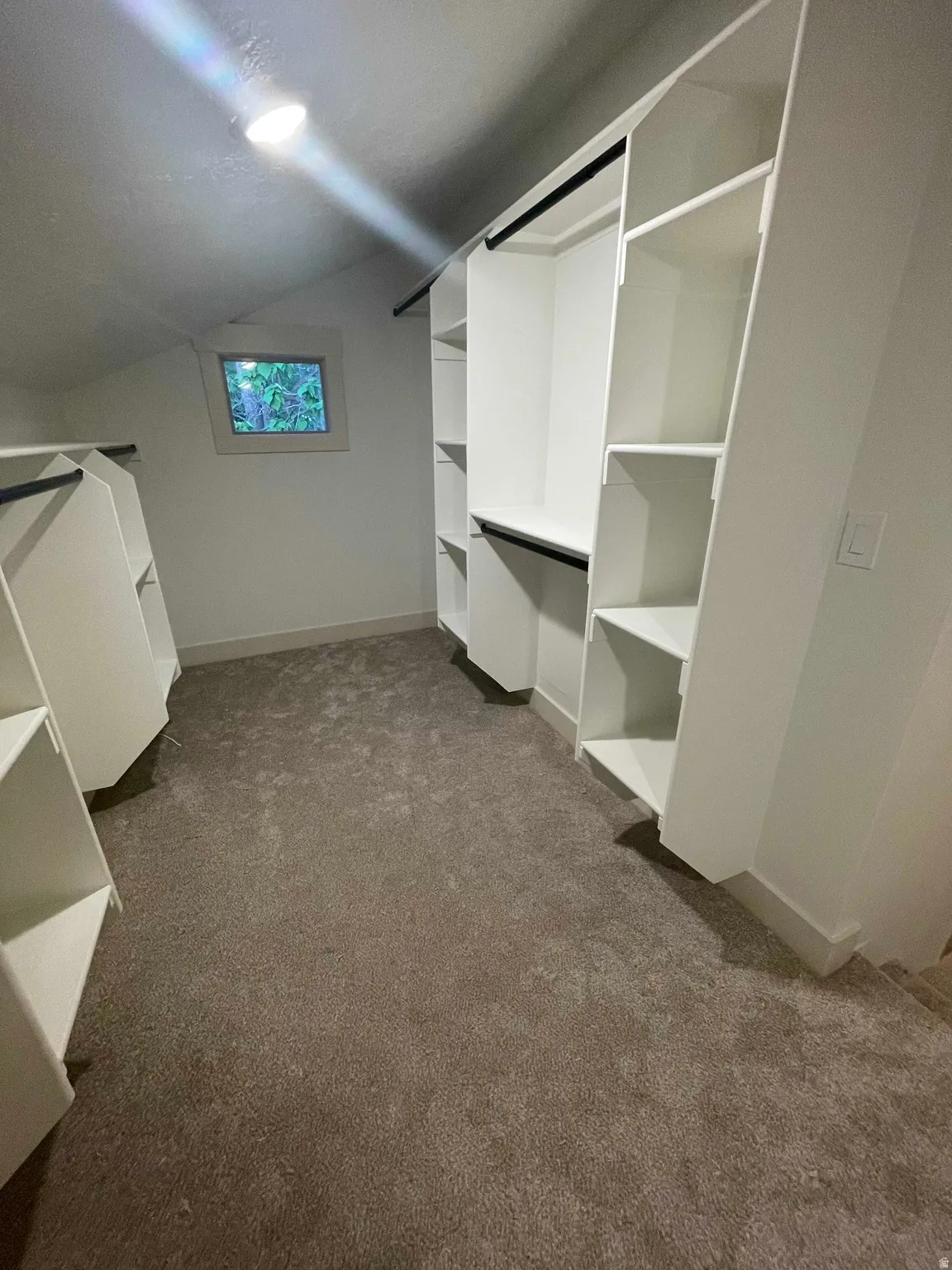 Organized closet space featuring built-in shelving, hanging rods, and recessed lighting